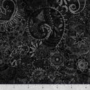 Black wide quilt backing fabric with a bohemian abstract design with a ruler at the bottom to show scale.