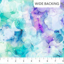 Wide quilt backing fabric with a colorful watercolor-like pattern with shades of blue, green, and purple with a ruler at the bottom to show scale.