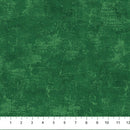 A close-up of a dark green wide quilt backing fabric with a dark green distressed looking, mottled pattern, shown with a white ruler at the bottom indicating scale.