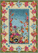 Multicolored quilt featuring a center panel with hummingbirds, flowers and a nest with eggs, surrounded by pieced quilt blocks and a green border.